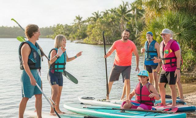 Local athletes testing paddles and outdoor gear beside Lake Victoria in North Palm Beach